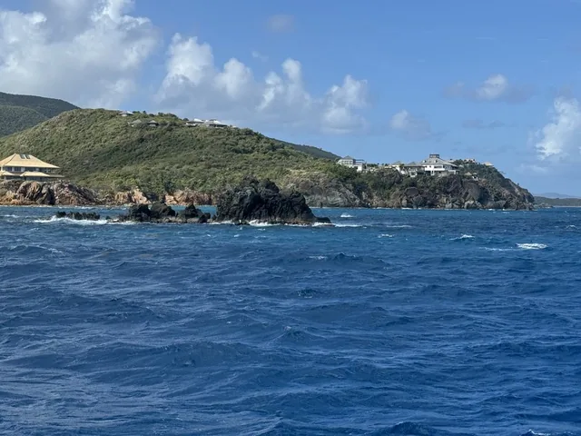 Rocky cliffs and clifftop villas on the St. Thomas coastline seen from the deck of Stella Blue catamaran