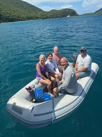 Guests and crew aboard the Stella Blue dinghy heading ashore in a calm turquoise Virgin Islands cove