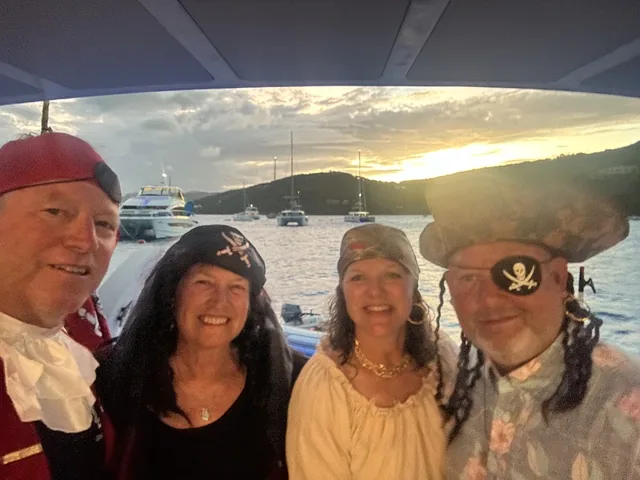 Four guests in full pirate costumes posing under the aft hardtop of Stella Blue at sunset in the USVI