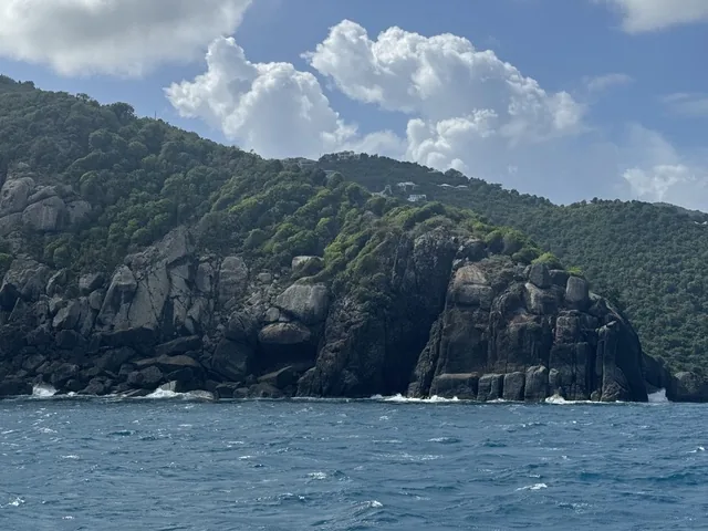 Dramatic granite headland and green hillside on a Virgin Islands coastline from Stella Blue underway
