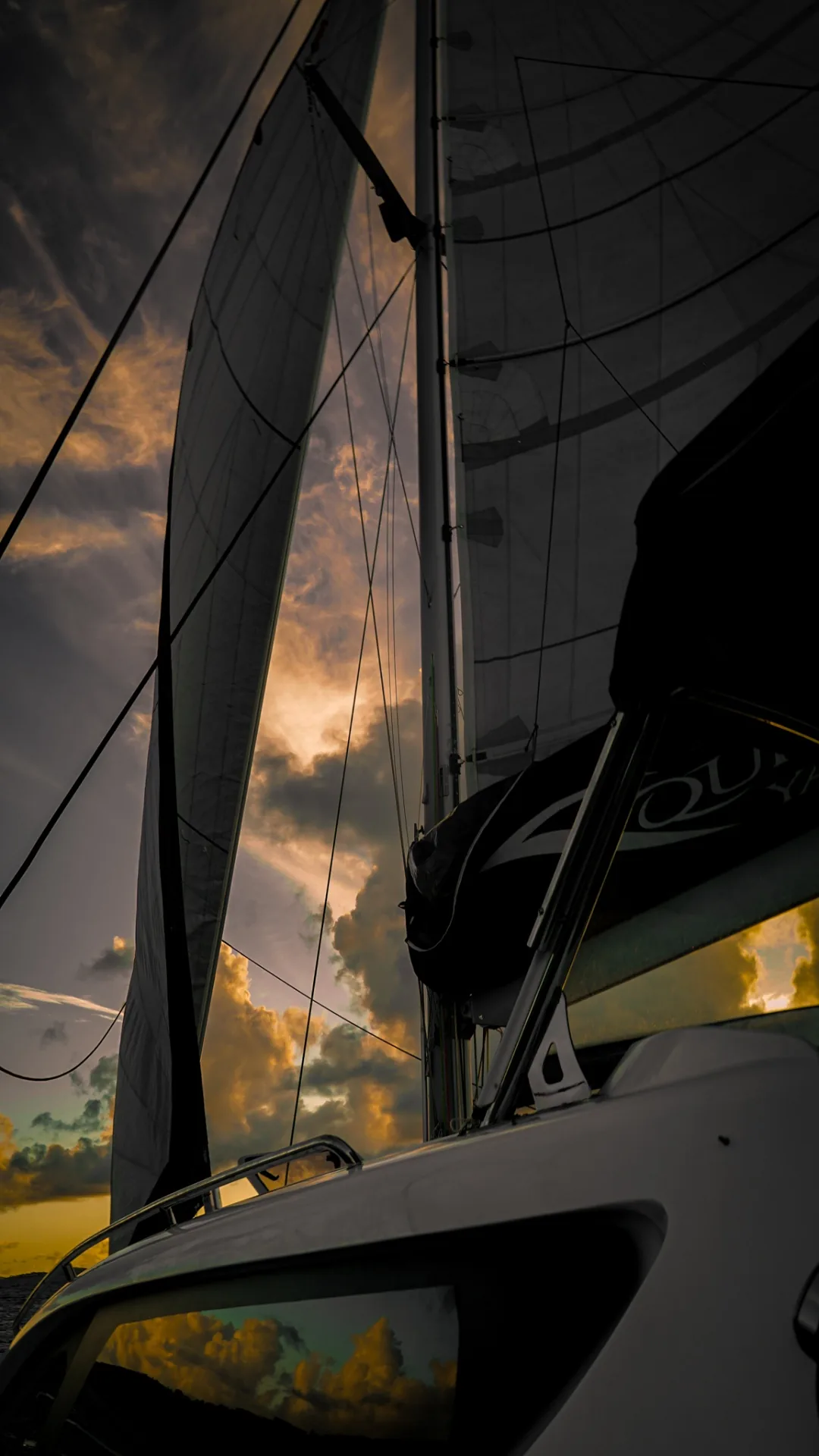 Sails silhouetted at sunset aboard the Xquisite X5 catamaran Stella Blue
