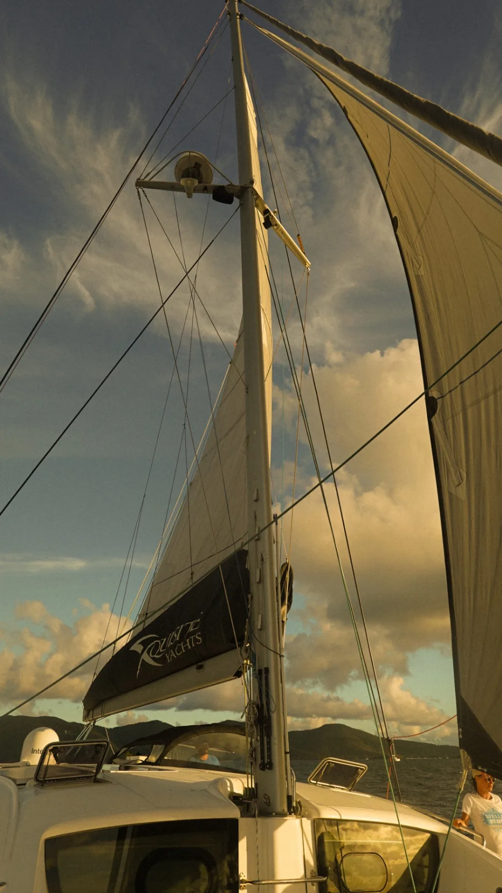 Mainsail and Xquisite Yachts boom cover with the rig of Stella Blue catamaran in golden afternoon light