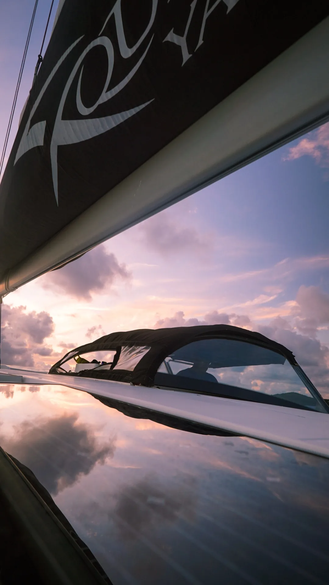 Boom and bimini reflecting a pastel sunrise on the deck of Stella Blue