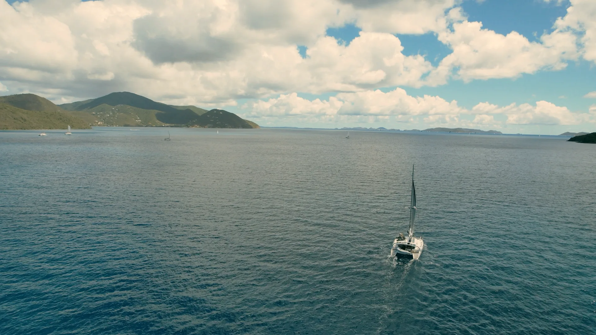 Wide aerial of Stella Blue under sail in the Virgin Islands with open water and layered islands in the distance